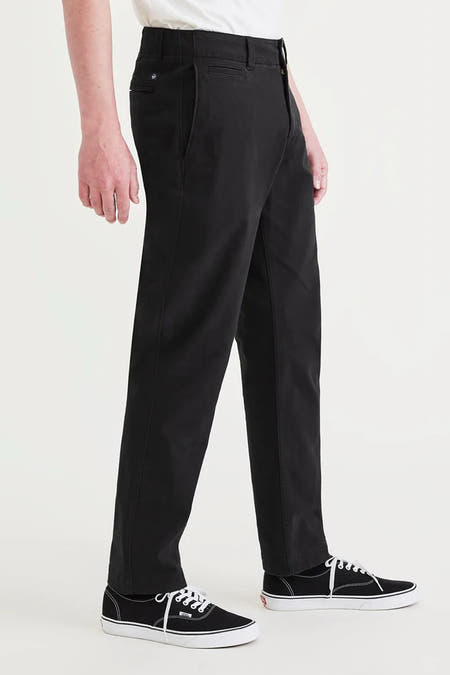Zwarte chino van DOCKERS, met zijzakken en zwarte Vans-schoenen.
