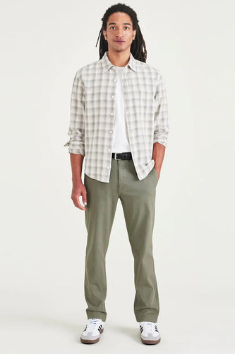 Man in geruit overhemd, groene broek en witte sneakers.