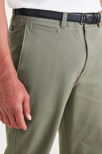 Groene chino van DOCKERS, met een zwarte riem en een verborgen zak op de heup.
