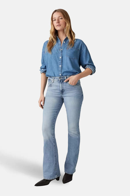 Jeans flared van lichtblauw denim van Levi's®, gedragen met een blauw denim overhemd en zwarte laarzen.
