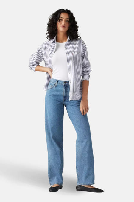 Jean droit bleu denim mi-mollet de Levi's, porté avec un chemisier blanc et des ballerines noires, en vue latérale.