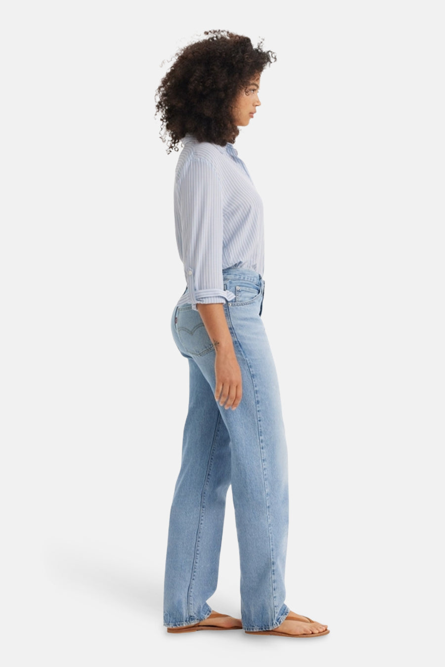 Jean droit bleu clair de Levi's, porté avec une chemise rayée bleue, vue de profil.