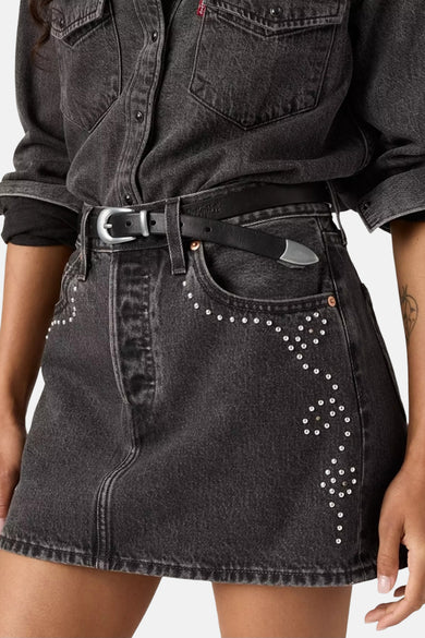 Korte donkergrijze denim rok van Levi's, versierd met zilverkleurige studs langs de zakken en een zwarte riem.
