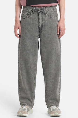 Jean ample gris foncé de Levi's, avec poches italiennes et porté avec des baskets beiges.