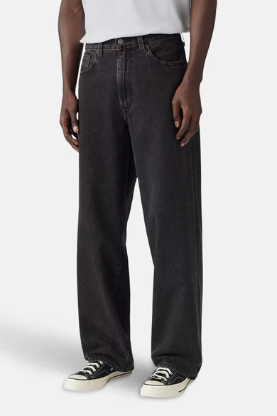 Wijde jeans van donkergrijs denim van Levi's®, gecombineerd met witte sneakers en een wit shirt.