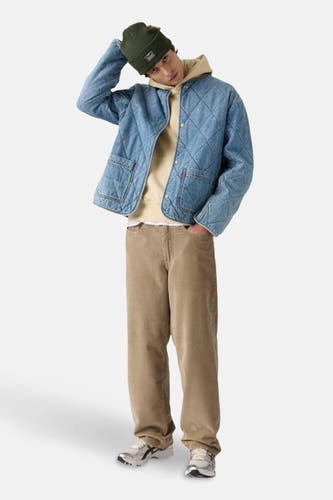 Beige colorbroek van Levi's, met wijde pijpen en gedragen met een beige hoodie en een denim jas.