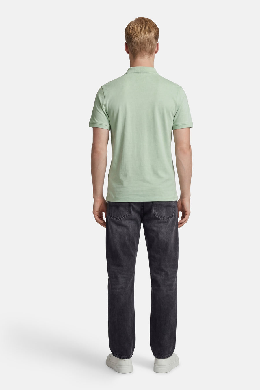 Groene polo van Levi's®, achterzijde, met geribbelde kraag. Gedragen met donkergrijze jeans en witte sneakers.