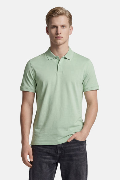 Polo verte Levi's® verte de couleur verte avec deux boutons et un logo discret, portée par un homme en jean foncé.