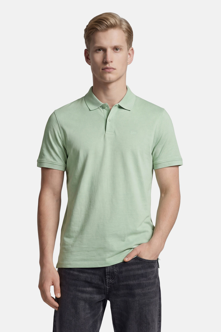 Groene polo van Levi's® met twee knopen en subtiel logo, gedragen door een man in donkere jeans.