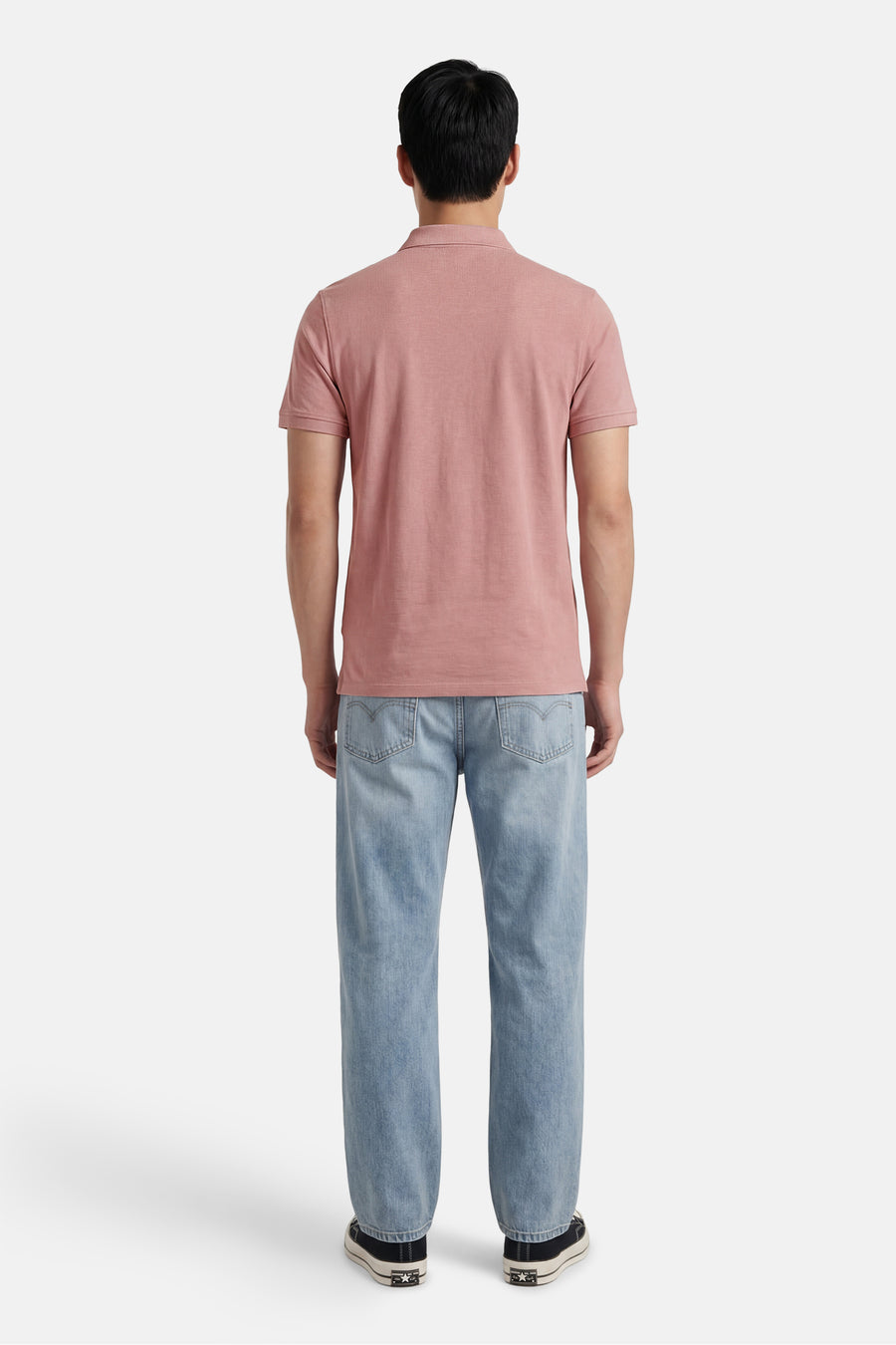 Roze polo van Levi's® met korte mouwen, achterzijde zichtbaar, gecombineerd met lichtblauwe jeans en zwarte sneakers.