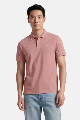 Roze polo van Levi's® met korte mouwen en een discreet logo op de borst, gedragen door een man met een lichte spijkerbroek.