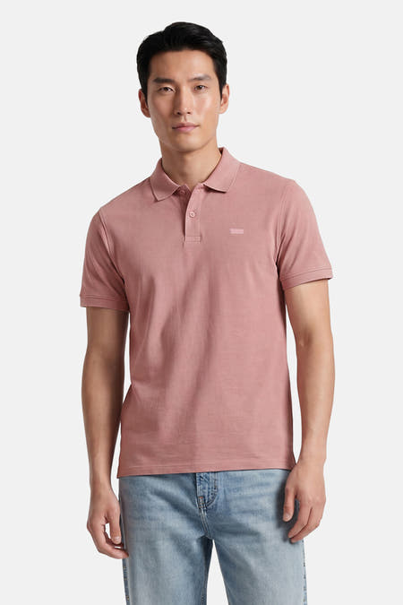 Roze polo van Levi's® met korte mouwen en een discreet logo op de borst, gedragen door een man met een lichte spijkerbroek.