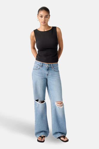 Wijd uitlopende jeans in blauw denim van Levi's®, met scheuren op de knieën en gedragen met een zwarte tanktop.
