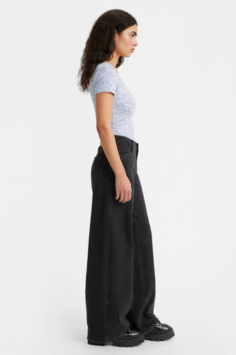 Jean wide Levi's noir, avec des jambes larges et porté avec un t-shirt bleu et des chaussures noires.