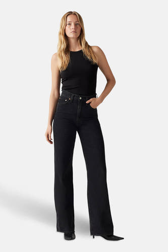Zwarte wide jeans van Levi's, gecombineerd met een zwarte ribgebreide top en zwarte hakken.
