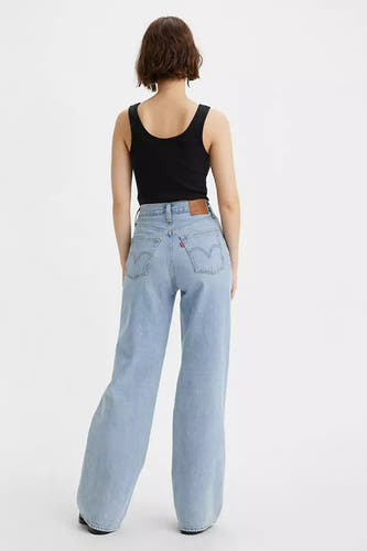 Wijde jeans van lichtblauw denim van Levi's, gecombineerd met een zwarte tanktop, gezien van achteren.
