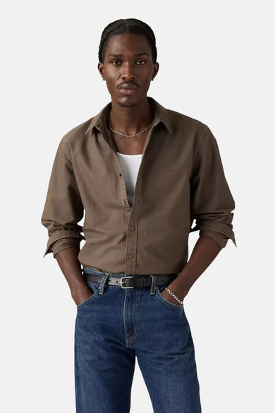 Bruin hemd met lange mouwen van Levi's, met knoopsluiting en gedragen over een wit shirt, gecombineerd met een donkere jeans en riem.
