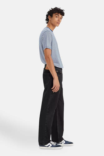 Jeans straight van zwart denim van Levi's®, gecombineerd met gestreept t-shirt en blauw-witte sneakers, zijaanzicht.
