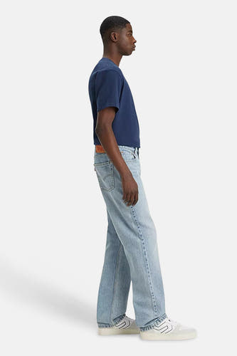 Jean en denim bleu clair droit de Levi's, montré en vue latérale, associé à un t-shirt bleu foncé et des baskets blanches.