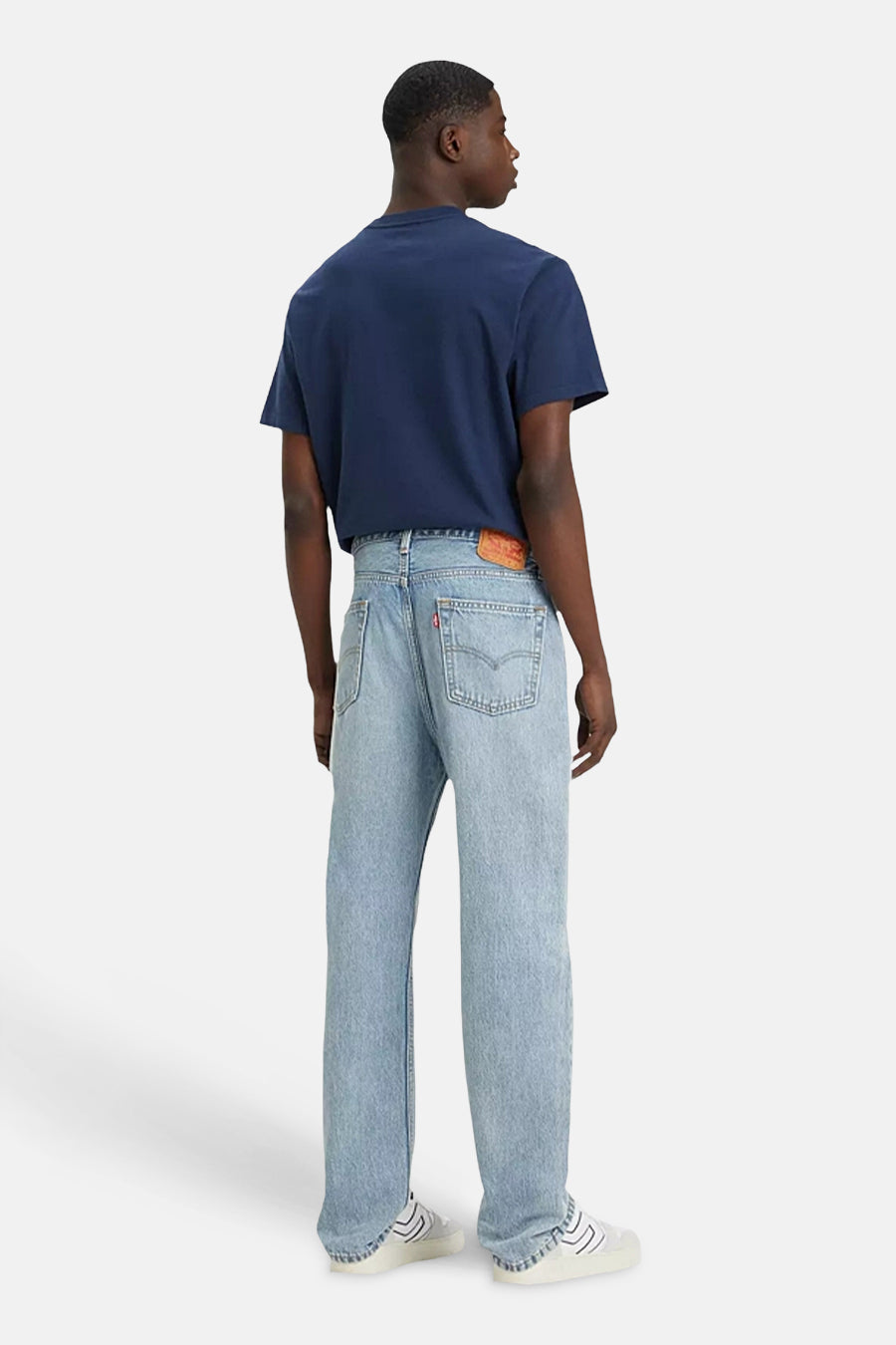 Jean en denim bleu clair droit de Levi's, vu de dos, associé à un t-shirt bleu marine et des chaussures blanches.