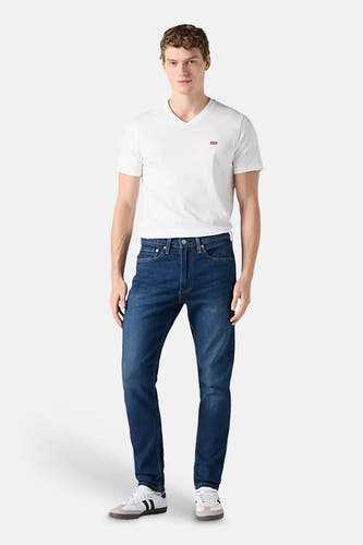 Jeans straight mid blue denim van Levi's, gedragen met een wit T-shirt en witte sneakers.