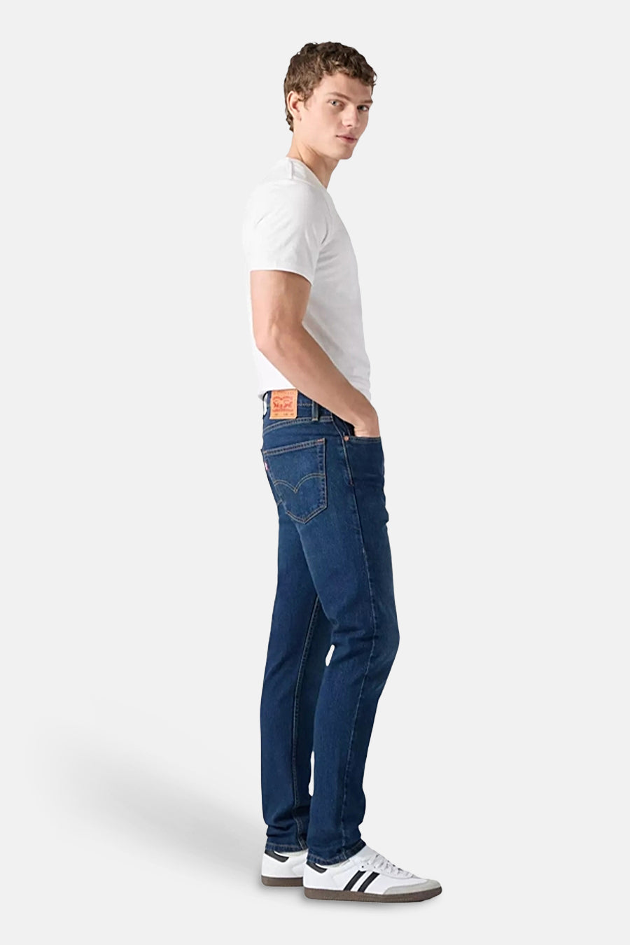 Jeans straight van blauw denim van Levi's, met rode merklabel achterop en witte sneakers.