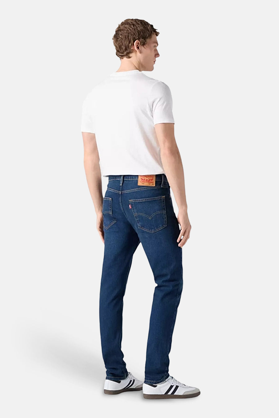 Straight jeans van blauw denim van Levi's, gezien van achteren, gedragen met een wit T-shirt en witte sneakers.
