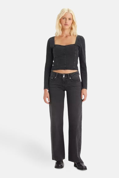 Jean délavé de Levi's Youth, avec fermeture à double bouton, porté avec un haut sombre à longues manches.
