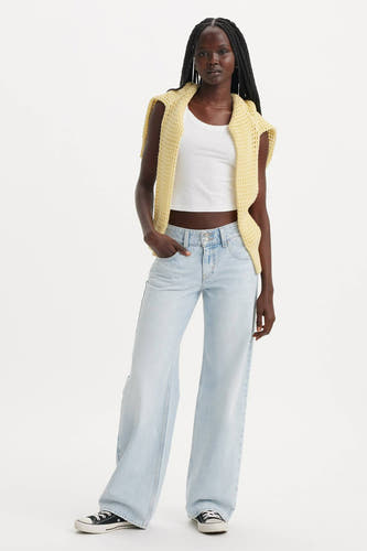 Jean bleu clair droit de Levi's, associé à un chemisier blanc et une veste tricotée jaune.