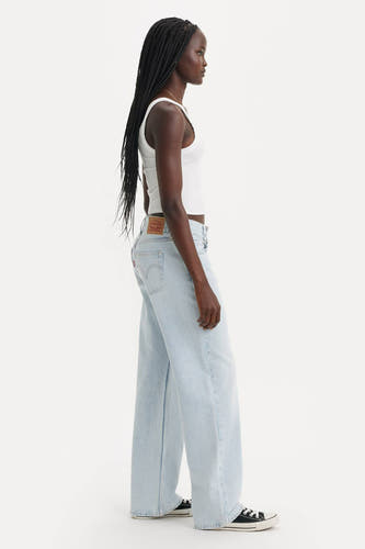Jean droit bleu clair de Levi's, avec un chemisier blanc et des baskets noires.