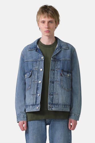 Jeansjas van blauw denim van Levi's, met knoopsluiting en zakken, gedragen met een groene trui en jeans.
