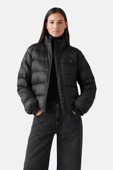 Veste courte noire de Levi's avec des manches longues, une fermeture éclair et portée avec un gilet noir et des jeans foncés.