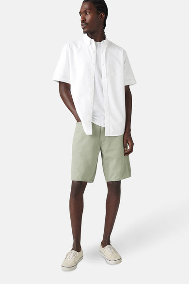 Groene short van Levi's®, gecombineerd met een wit T-shirt en een wit overhemd, staand gepresenteerd.
