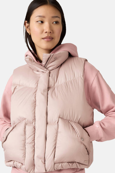 Vrouw met roze gewatteerd vest en hoodie.