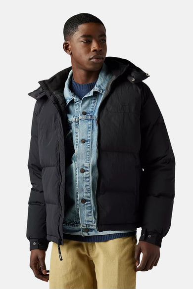 Zwarte korte jas van Levi's, met capuchon, over een denim overhemd en een blauwe trui.