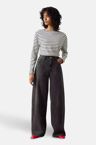 Zwarte straight jeans van Levi's, gedragen met een gestreepte top en rode schoenen.
