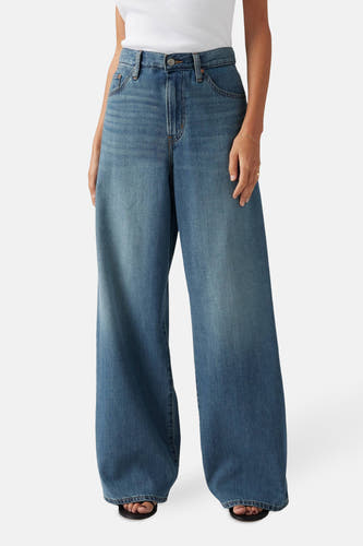 Jeans straight van blauw denim van Levi's®, wijd uitlopend model gedragen met een witte top en sandalen.
