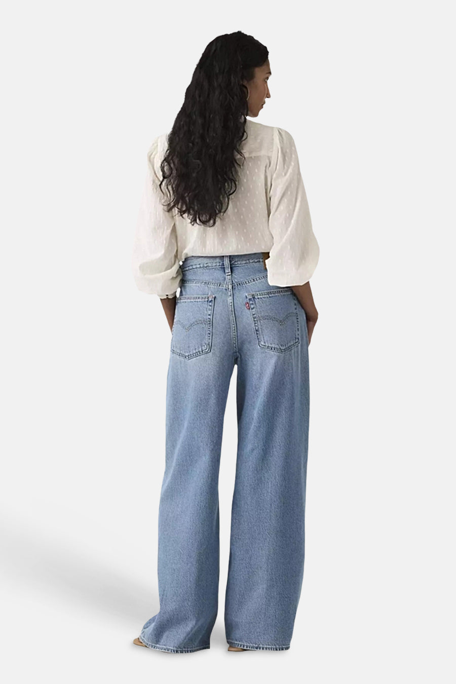 Blauwe straight jeans van Levi's, gezien van achteren, met steekzakken en een witte blouse.
