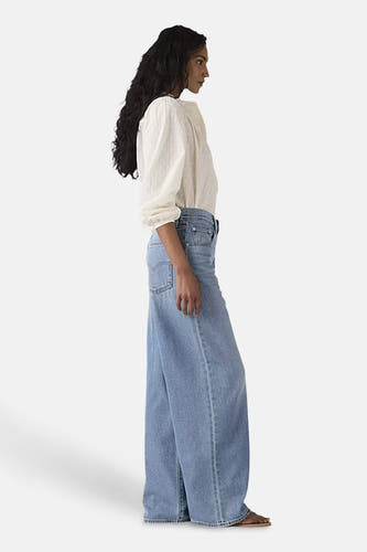 Blauwe straight jeans van Levi's, met een losse pasvorm en gedragen met een witte blouse.
