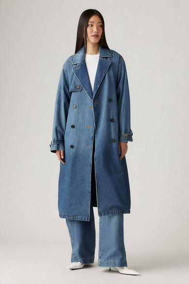 Donkerblauwe denim trenchcoat van Levi's® met dubbele rij knopen, riemdetails en rechte pasvorm, gedragen met witte top en jeans.
