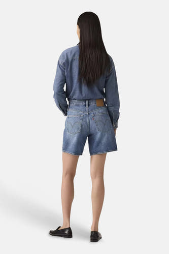 Mid blauwe denim short van Levi's®, achterkant gedragen door een vrouw met een denim overhemd en zwarte instappers.