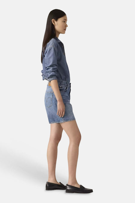 Mid blauwe denim short/rok van Levi's® in zij-aanzicht, gedragen door een vrouw.
