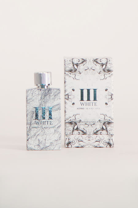 Parfum blanc d'Astrid Black Label, avec motif marbré, à côté de l'emballage coordonné avec une spirale noire et blanche.