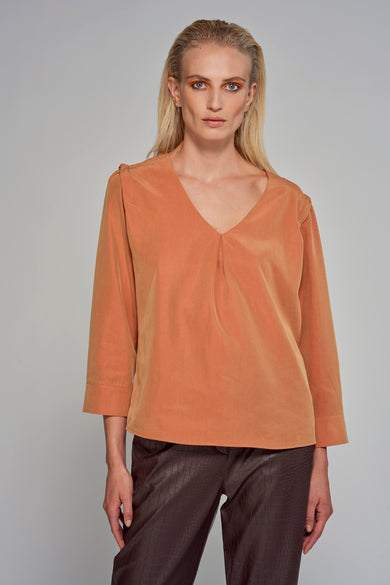 Oranje blouse met driekwartmouwen van Astrid Black Label, met een V-hals en gedragen met een broek met krokodillenprint.

