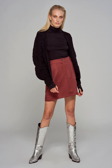 Zwart gilet van Astrid Black Label, gedragen over een zwarte coltrui en een rode rok, met zilveren laarzen.
