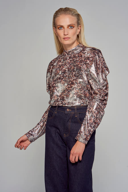 Zilveren blouse van Astrid Black Label met panterprint en lange mouwen, gecombineerd met een donkere jeans.
