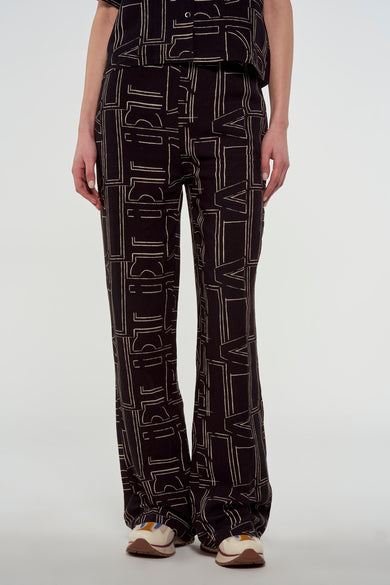 Zwarte broek van Astrid Black Label met beige geometrisch patroon en uitlopende pijpen, gecombineerd met sneakers.
