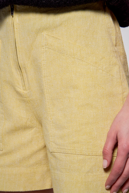 Gele short van Astrid Black Label met zakken en een ritssluiting, close-up.
