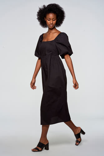 Zwarte jurk met korte mouwen van Astrid Black Label, met vierkante halslijn en zwierige, zwarte muiltjes.
