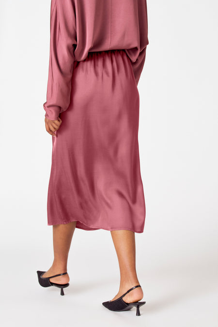 Robe rose d'Astrid Black Label, vue de l'arrière, avec des talons noirs.